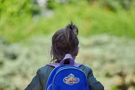 Un.e enfant de dos avec un cartable.